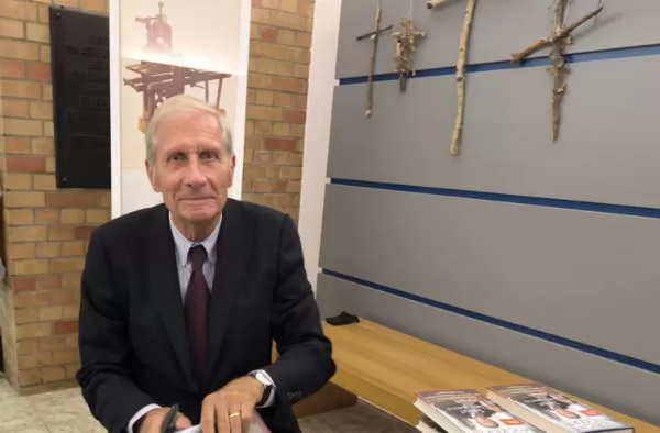 Ulrich Wickert schaut in die Kamera und signiert seine Bücher
